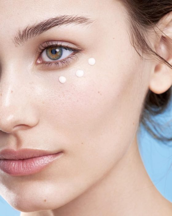 Chica aplicando crema de contorno de ojos