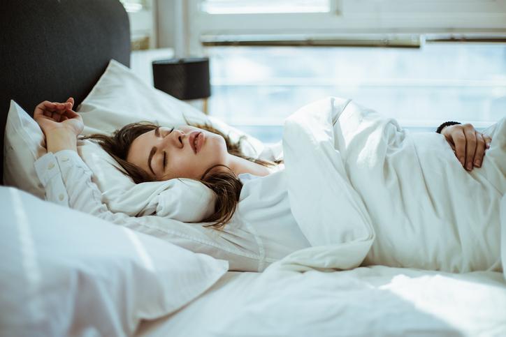 Mujer durmiendo en cama, con pijama y edredón