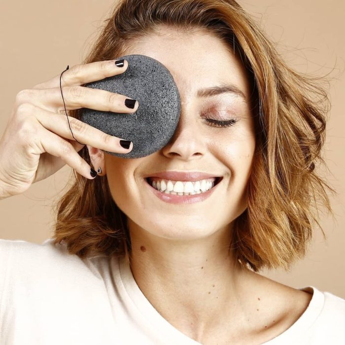 Chica sonriendo con esponja Konjac en uno de sus ojos