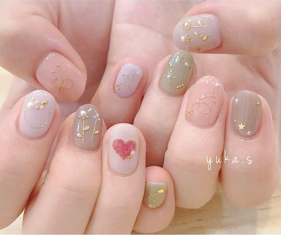 Manicura en tono rosa, gris y verde olivo con decoración de flores doradas y un corazón