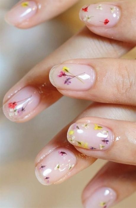 Manicura en efecto cristal con decoración de flores amarillas y lilas