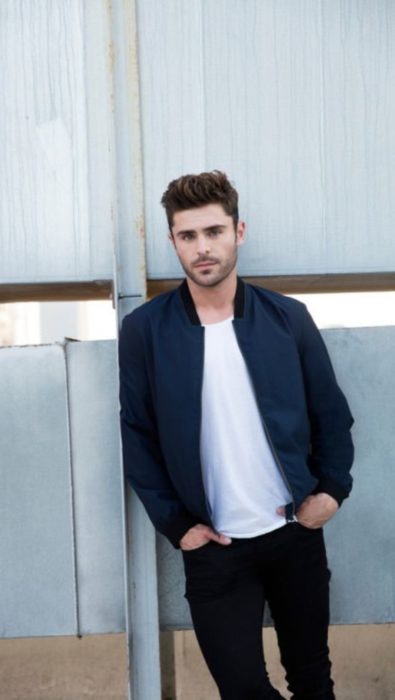 Fondo de pantalla para celular con Zac Efron apoyado en un poste de concreto