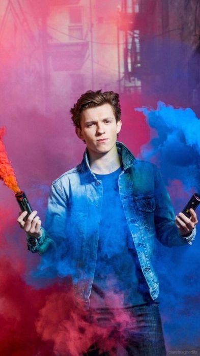 Fondo de pantalla para celular con Tom Holland sosteniendo humo de colores