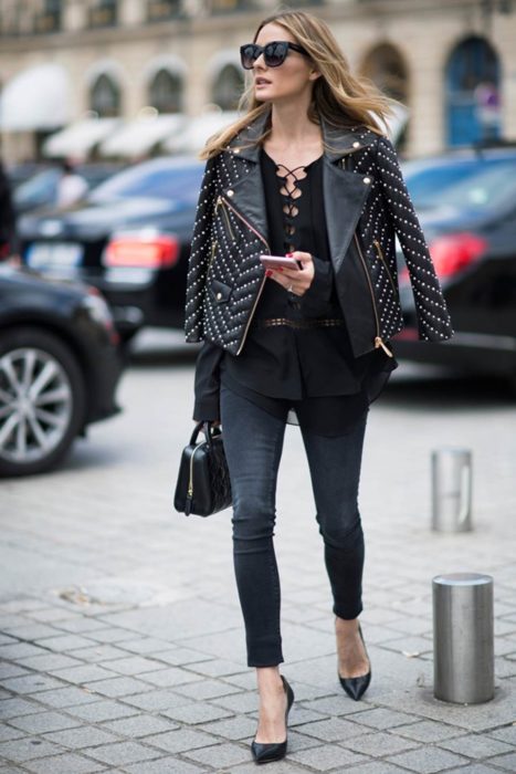 Olivia Palermo caminando por las calles mientras mira su celular 