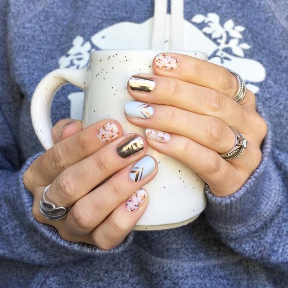 Manicura en azul cielo, dorado y decoraciones en rojo