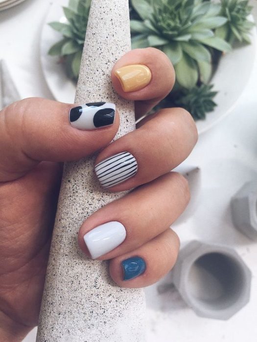 Manicura en tonos azul, blanco, amarillo y con líneas en negro