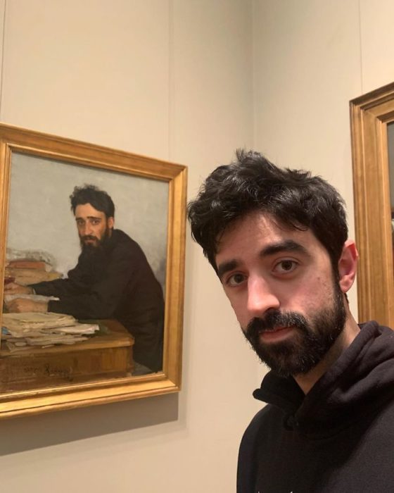 Hombre tomando una selfie frente a una pintura de la edad media