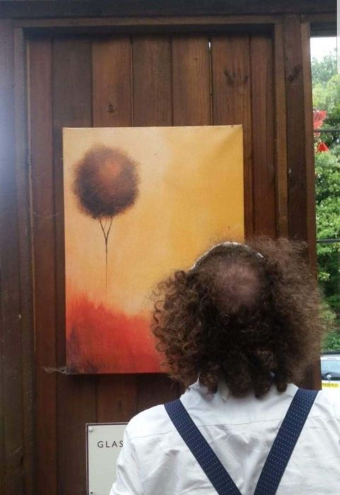 Hombre de espaldas admirando una pintura de un globo en el atardecer