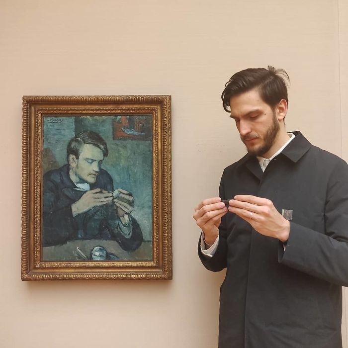 Hombre revisando su teléfono celular junto a una pintura