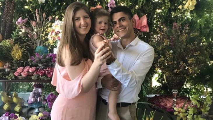 Pareja de esposos sosteniendo a una niña en brazos mientras se toman una foto