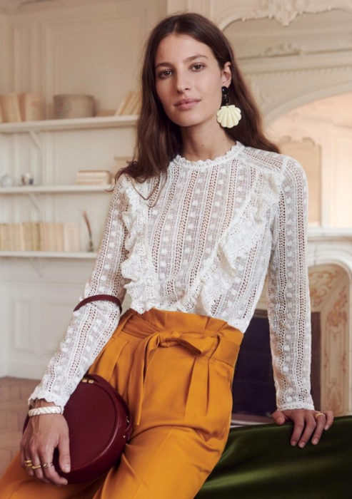 Atuendos formales y juveniles para oficina; blusa blanca de holanes y encaje, aretes de conchas, pantalón mostaza