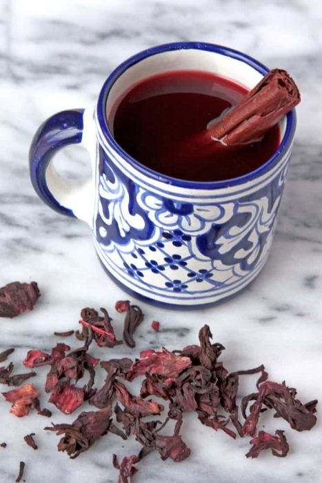 Té de canela en taza adornada, con jamaica sobre mesa de mármol