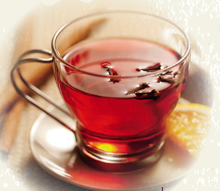Infusión de clavo de olor en taza de cristal con una rodaja de naranja
