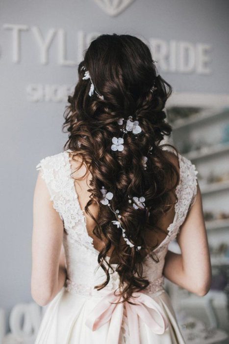 Semirecogido de novia en cabello rizado tipo twist con adornos florales