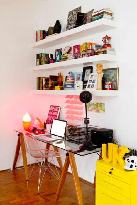 Escritorio con mesa de cristal, repisas blancas y mesa amarilla