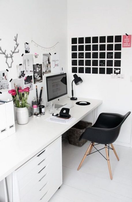Escritorio blanco y paredes del mismo color, silla negra y calendario negro que crean una combinación perfecta