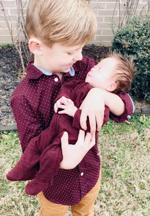 Rayce sosteniendo a su hermanito Tripp