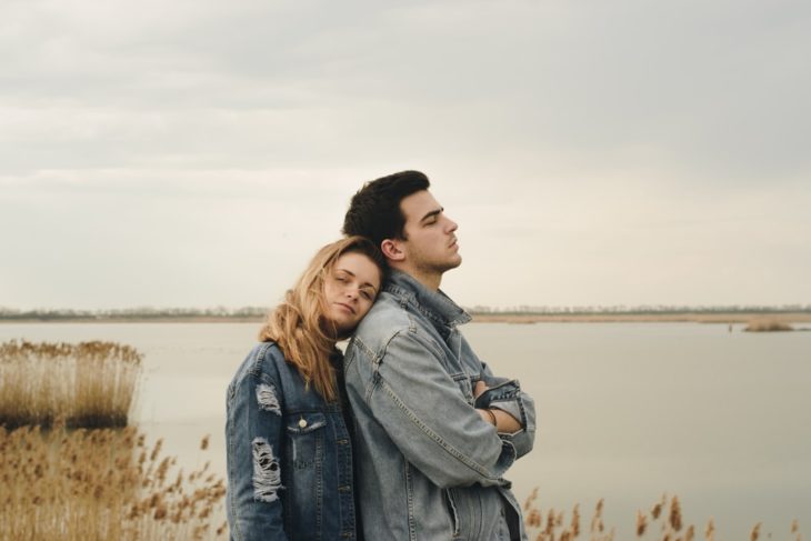 Pareja de novios en un lago, chica recargada en la espalda de su novio