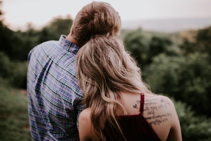 Pareja de novios de espaldas apoyados el uno en el otro en un bosque