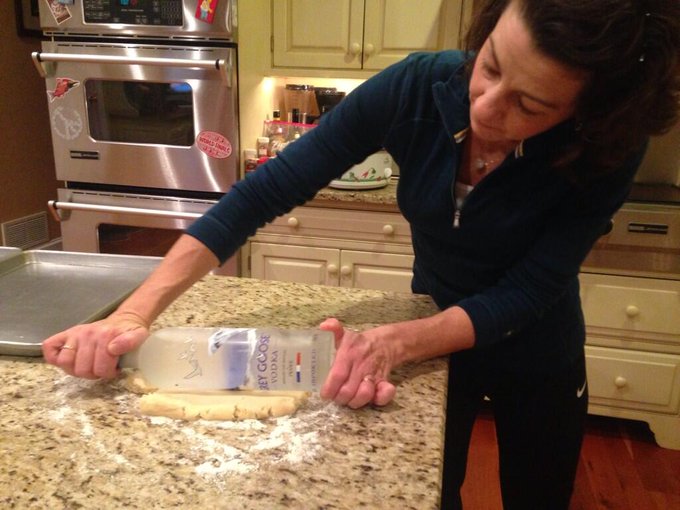 Mamá usando una botella para aplanar masa de galletas 
