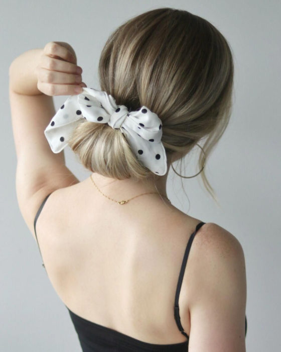 Peinados para San Valentín; cabello rubio recogido en un chongo bajo, con un pañuelo blanco de lunares negros