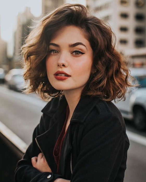 Peinados para San Valentín; mujer posando para una foto en la calle, con cabello bob corto, ondulado y suelto