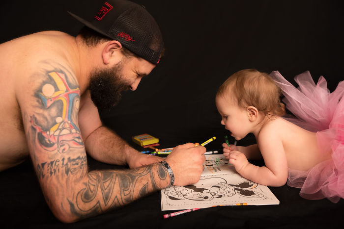 Padre e hija recostados en el suelo coloreando un libro de arte