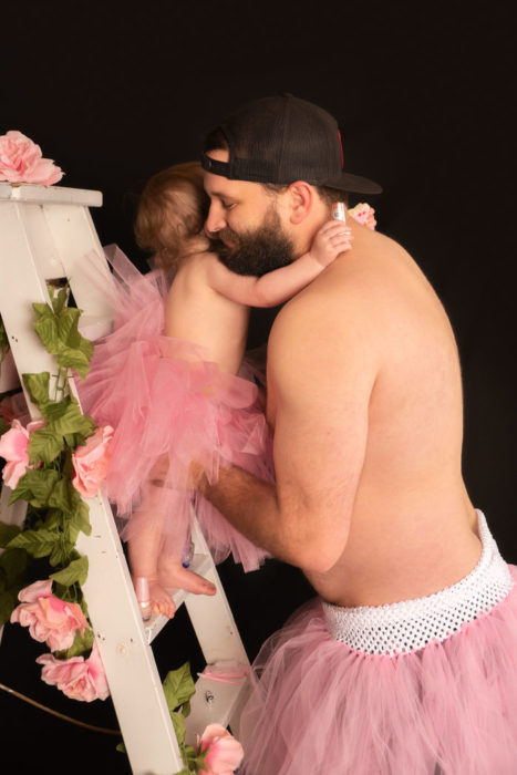 Padre e hija usando tutús, abrazados sobre una escalera