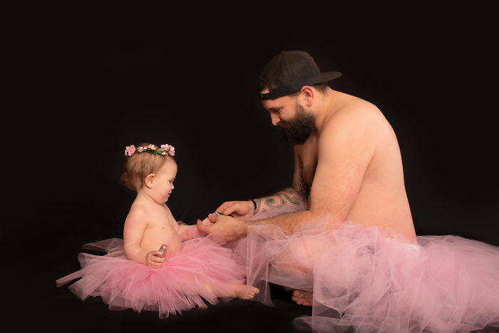 Padre e hija usando tutús sentados en el piso pintándose las uñas