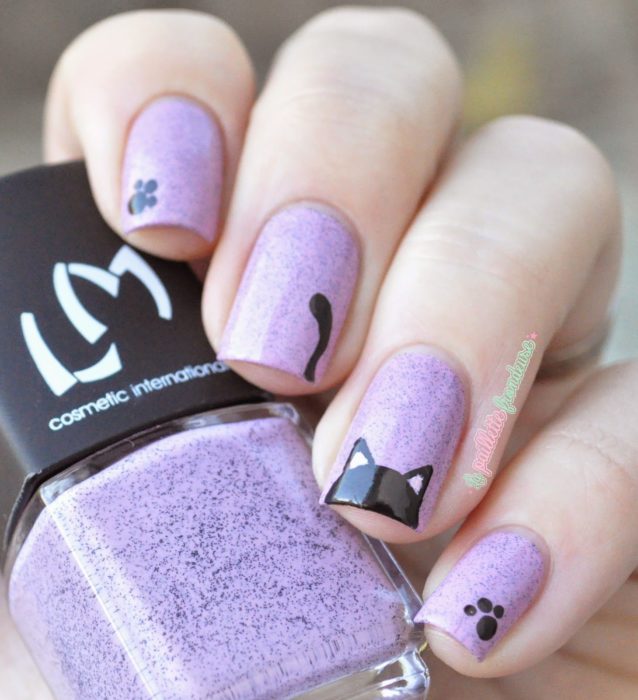 Chica con las uñas pintadas de color morado y decoradas con un gato