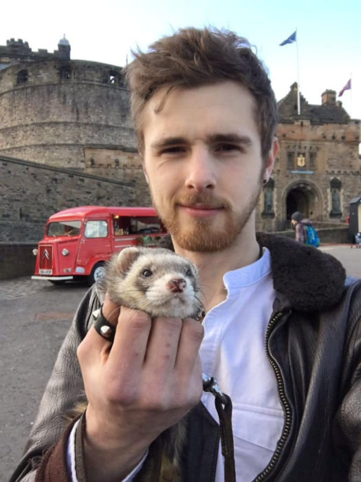 Chico posando junto a su hurón en un monumento de Inglaterra