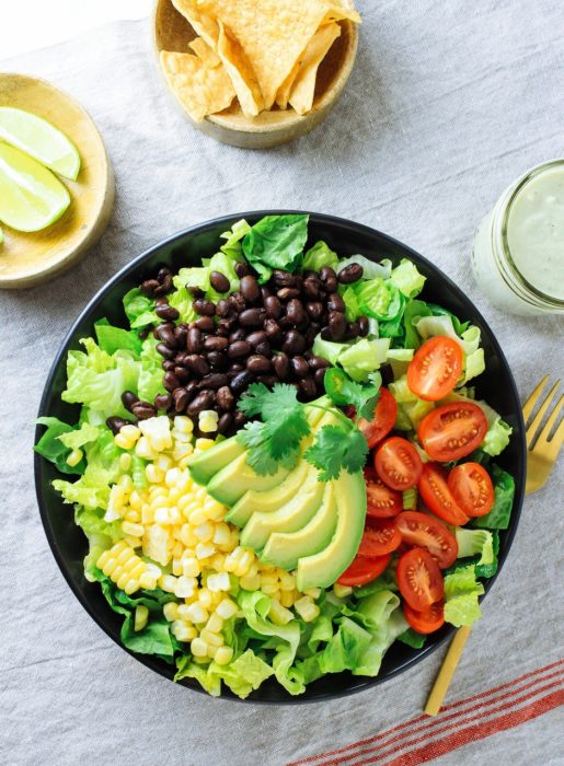 Plato de comida: ensalada con legumbres, limón y algunos totopos