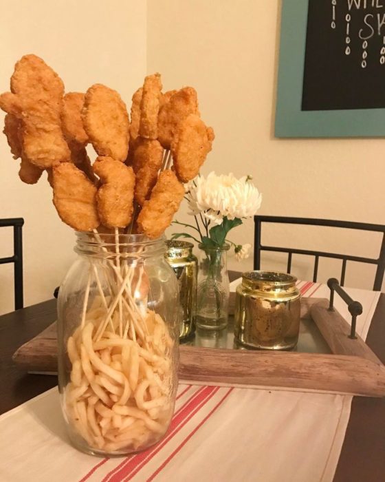Ramo de nuggets puesto dentro de un envase que tiene papas fritas 