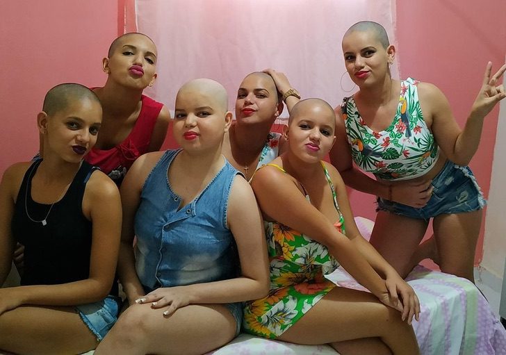 Grupo de mujeres luciendo su cabeza sin cabello apoyando a su amiga con leucemia