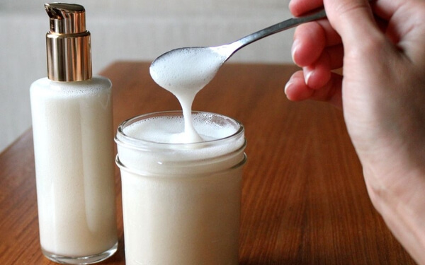 Leche limpiadora casera en recipiente de cristal con cuchara de metal