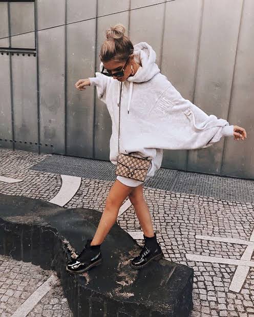 Chica con botas estilo militar en negro y hoodie amplia en gris