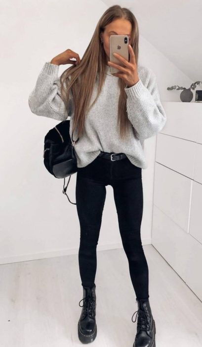 Chica con jeans negros, blusa gris y botas Dr. Martens