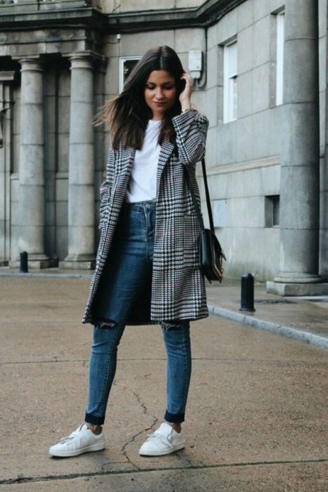 Chica con un saco, jeans y tenis blancos