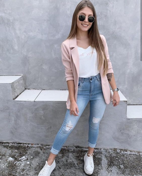 Chica con un outfit de jeans, blazer y blusa rosa con tenis blancos