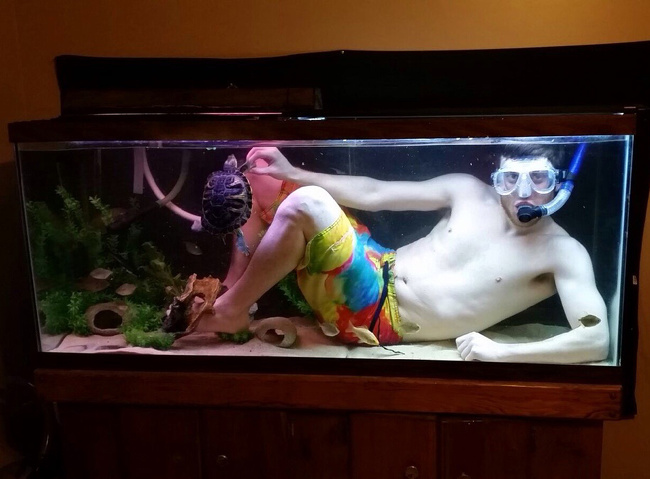 Chico vestido de buzo y dentro de una pecera para tortugas