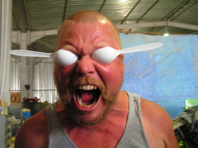 Chico con dos cucharas puestas en los ojos mientras tiene rostro de enojo