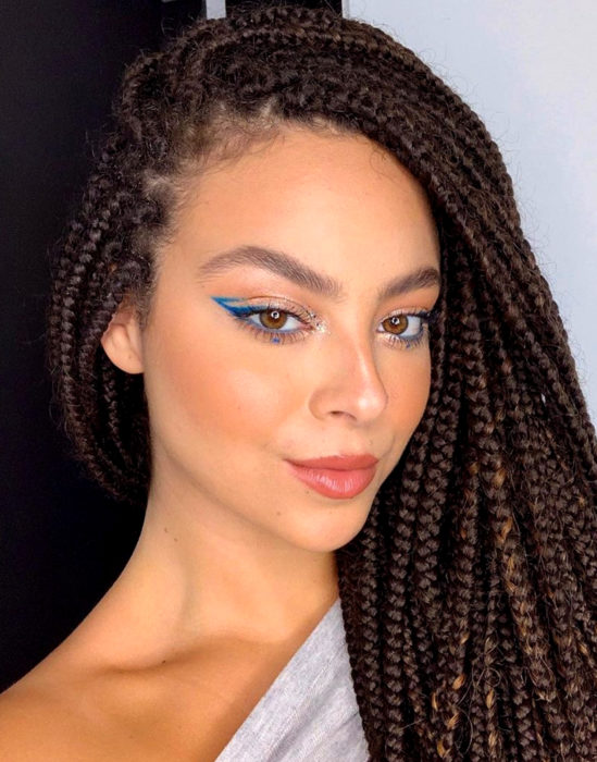 Maquillaje tendencia para el 2020; delineado gráfico o flotante color azul; mujer afroamericana con trenzas