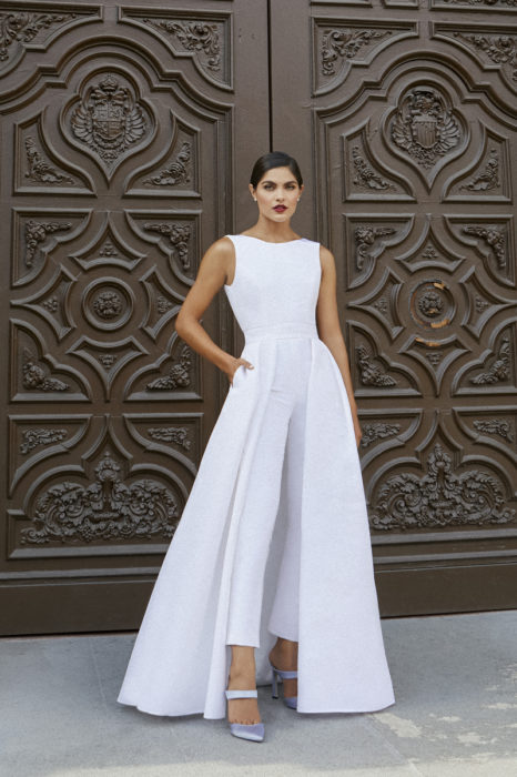 Chica usando un jumpsuit de color blanco con capa a partir de las caderas
