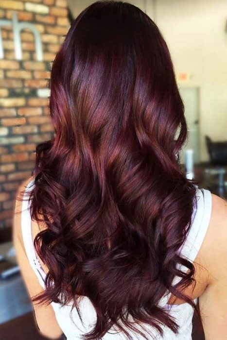 Chica de espaldas con cabello largo, teñido en tono cherry wine con luces