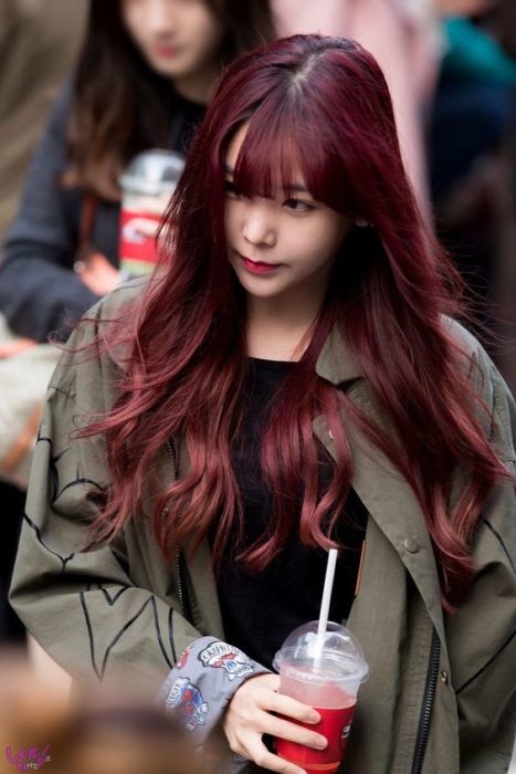 Chica con cabello largo, caminando en la calle y mostrando su cabello en tono cherry wine