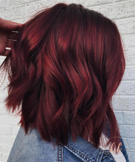 Chica de perfil mostrando su cabellera corta en tono cherry wine con ondas ligeras