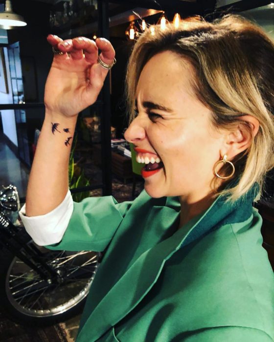 Emilia Clarke con saco demostrando su tatuaje de dragones
