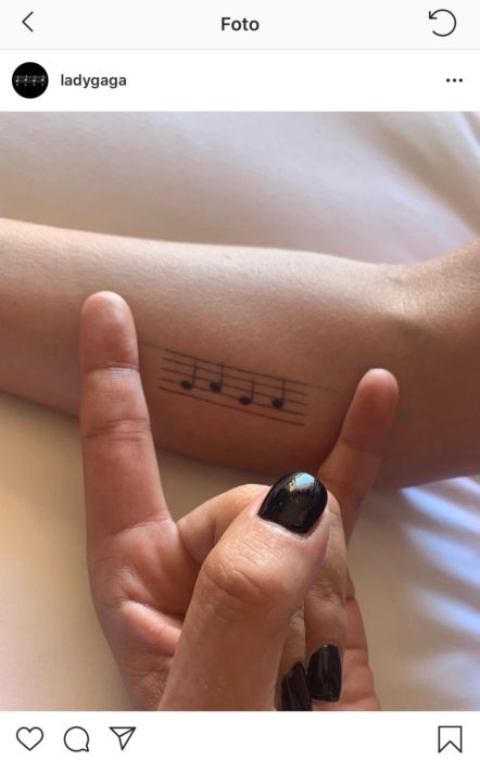 Lady Gaga mostrando su tatuaje de pentagrama musical