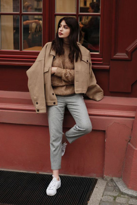 Chica con chaqueta color arena y pantalones ajustados grises