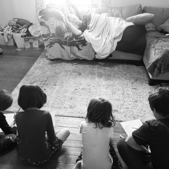 Niños sentados frente a su padre mientras lo dibujan